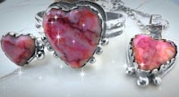 a pink stone heart shaped ring and a silver heart shaped ring