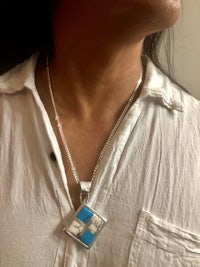 a woman wearing a necklace with a blue and white pendant