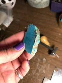 a person holding a piece of turquoise