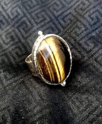 a silver ring with a tiger eye stone