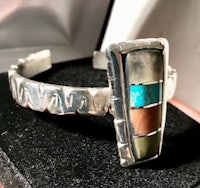 a silver cuff bracelet with a multi colored inlay