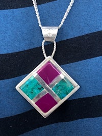 a silver pendant with a turquoise and pink stone
